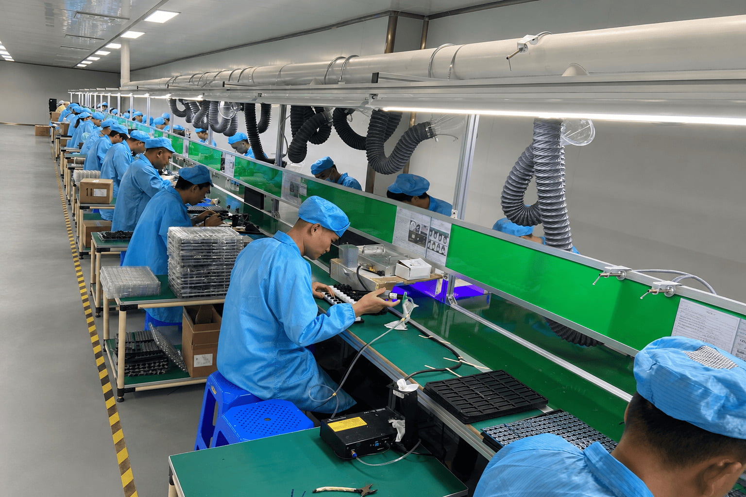Factory workers carefully assembling TWS earbuds on a production line